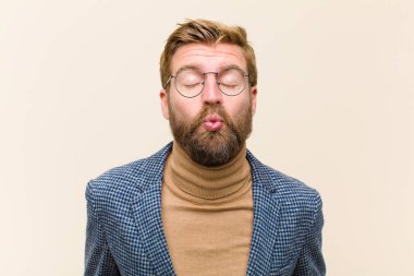 Genç sarışın iş adamı dudaklarını birbirine bastırıyor, tatlı, eğlenceli, mutlu, sevimli bir yüz ifadesiyle, öpücük yolluyor.