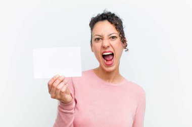 Beyaz duvarda pankartı olan genç ve güzel bir kadın.