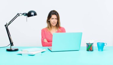 Genç ve güzel bir kadın dizüstü bilgisayarla çalışıyor şüphe ediyor ya da düşünüyor, dudağını ısırıyor ve kendini güvensiz ve gergin hissediyor.