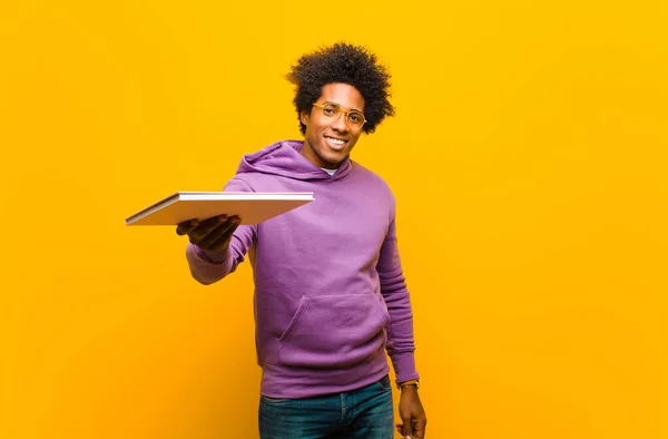 Jovem afro-americano com um livro contra fundo laranja — Fotografia de Stock