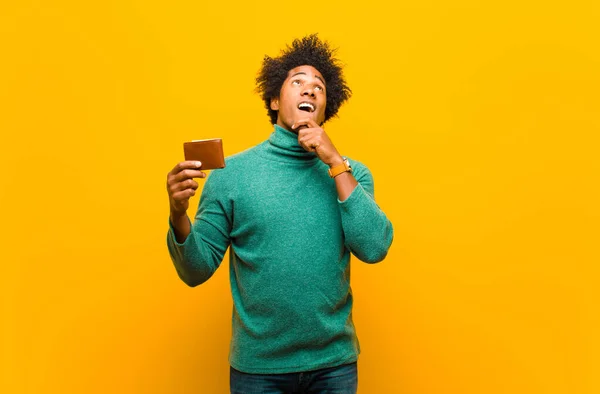 Young african american man with a wallet against orange backgrou — ストック写真