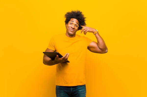 Jovem afro-americano com um tablet contra backgrou laranja — Fotografia de Stock