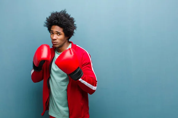 Mavi grunge duvarına karşı boks eldivenli genç siyahi adam — Stok fotoğraf