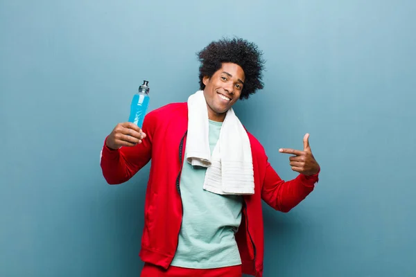 Ung svart man med en sport dryck mot blå grunge vägg — Stockfoto