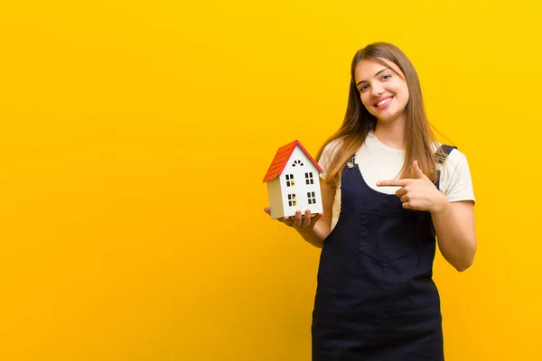 Giovane Bella Donna Con Modello Casa Contro Sfondo Arancione — Foto Stock