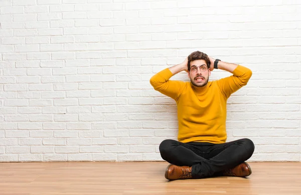 Joven Hombre Guapo Sentado Suelo Casa Contra Textura Pared Ladrillo —  Fotos de Stock