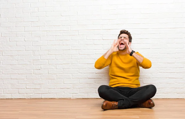 Junger Gutaussehender Mann Sitzt Auf Dem Fußboden Vor Einer Ziegelwand — Stockfoto