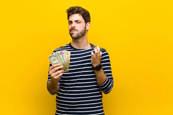 Fiatal jóképű férfi dollár bankjegyek ellen narancs backgrou — Stock Fotó