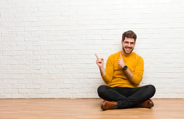 Joven Hombre Guapo Sentado Suelo Casa Contra Textura Pared Ladrillo — Foto de Stock