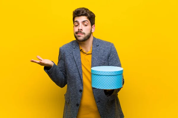 Jovem homem bonito com uma caixa contra fundo laranja — Fotografia de Stock