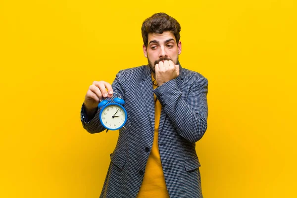 Jovem bonito homem com um despertador contra fundo laranja — Fotografia de Stock