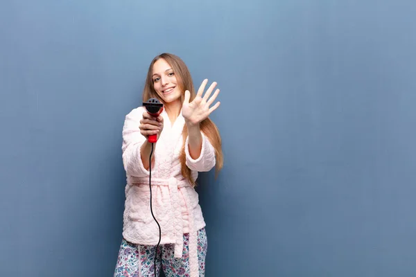 Young Pretty Woman Wearing Pajamas Holding Hairdresser Blue Wall Copy — Φωτογραφία Αρχείου