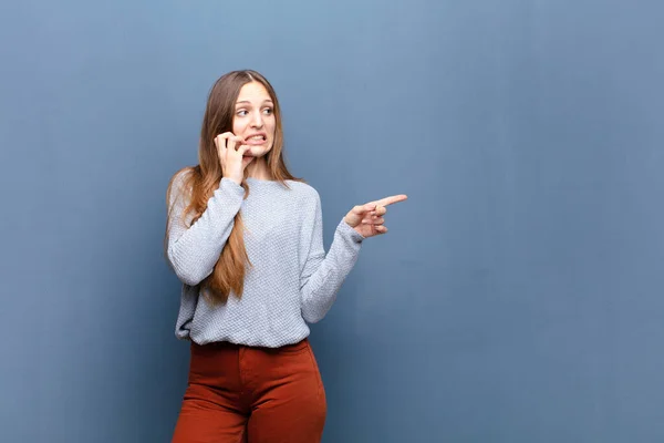 年轻漂亮的女人靠着蓝色的墙 有一个复制的空间 — 图库照片