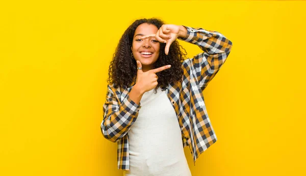年轻而漂亮的非洲裔美国女人感到快乐 友善而积极 面带微笑 双手靠着黄墙做肖像或相框 — 图库照片