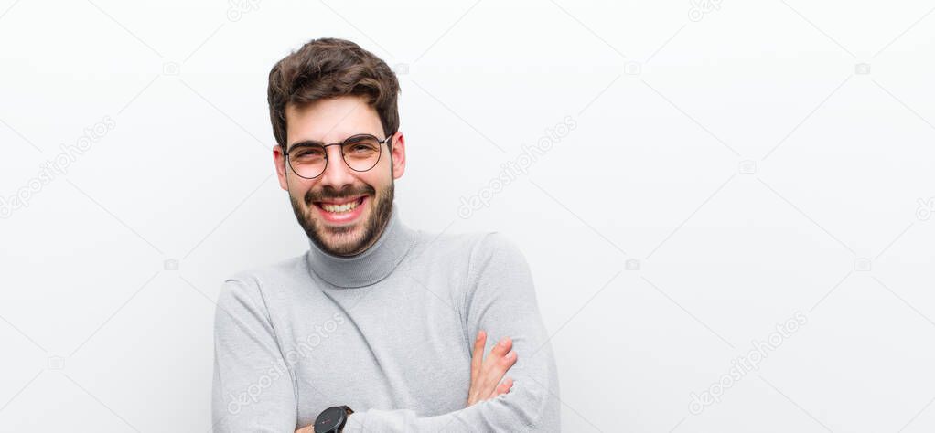 young manager man laughing happily with arms crossed, with a relaxed, positive and satisfied pose against white wall