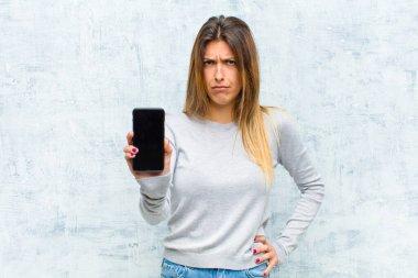 Akıllı telefonlu güzel bir kadın grunge duvarına karşı.