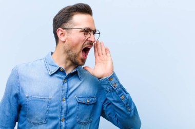 Genç yakışıklı adam öfkeyle bağırıyor kenardaki boşluğu kopyalasın diye, eli ağzının yanında.