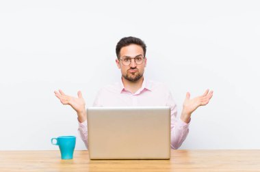 Genç yakışıklı iş adamı şaşkın ve şaşkın hissediyor, şüpheci, farklı seçenekleri tartıyor veya komik bir ifadeyle seçiyor.