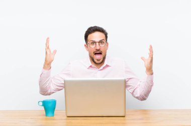 Genç yakışıklı iş adamı kendini mutlu, şaşkın, şanslı ve şaşırmış hissediyor. Zaferi iki eli havada kutluyor.