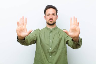 Genç yakışıklı adam ciddi, mutsuz, kızgın ve hoşnutsuz görünüyor. Ya da her iki avuçta da dur diyor.