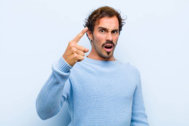 Kızgın agresif bir ifadeyle kameraya bakan genç yakışıklı bir adam. Kızgın, çılgın bir patron gibi görünüyor. Duvara yaslanmış.