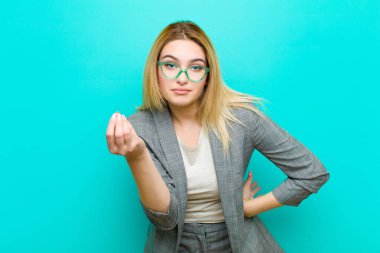 Genç, güzel sarışın kadın kapiş ya da para hareketi yapıyor, sana borçlarını ödemeni söylüyor! yassı duvara karşı