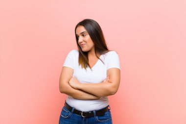 Genç ve güzel İspanyol bir kadın kızgın, sinirli, isyankar ve agresif hissediyor. Orta parmağını sallıyor, pembe duvara karşı savaşıyor.