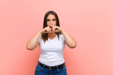 Genç, güzel İspanyol bir kadın stresli, endişeli, yorgun ve hayal kırıklığına uğramış, gömleğini çekmiş, pembe duvara karşı sorunlu görünüyor.
