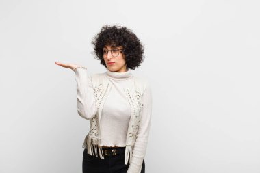 Genç, güzel, afro bir kadın mutlu ve gülümseyerek, elinde tuttuğu bir nesneye ya da konsepte bakıyor.