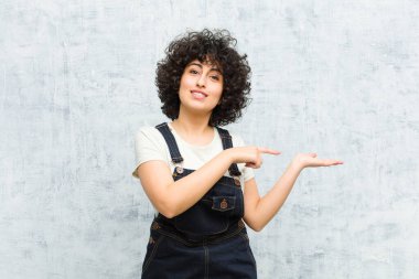 Genç, güzel afro kadın gülümsüyor, mutlu, kaygısız ve tatmin olmuş hissediyor, fotokopi alanındaki konsepte ya da fikre işaret ediyor.