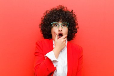 Ağzı ve gözleri açık, eli çenesinde genç ve güzel afro bir kadın. Hoş olmayan bir şok geçiriyor.