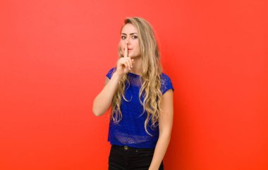 Genç sarışın kadın sessizlik ve sessizlik istiyor, parmaklarıyla ağzının önünde işaret ediyor, 