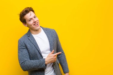 Genç kızıl saçlı adam heyecanlı ve şaşırmış görünüyor. Arkaplanı turuncu arka plana kopyalamak için yana ve yukarıya bakıyor.