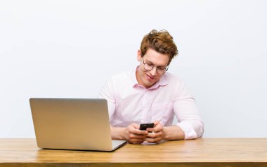 Genç kızıl saçlı işadamı masasında monil bir telefonla çalışıyor.