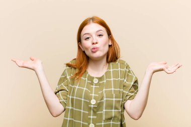 Genç kızıl saçlı güzel kadın şaşkın ve şaşkın hissediyor, şüpheci, ağırlıklı ya da komik ifadeli farklı seçenekler seçiyor.