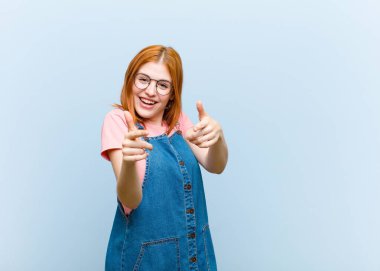 Genç kızıl saçlı güzel bir kadın kendini mutlu, havalı, tatmin olmuş, rahat ve başarılı hissediyor, kameraya bakıyor, seni seçiyor.