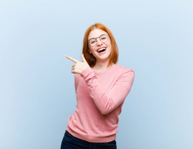 Genç kızıl saçlı güzel kadın heyecanlı ve şaşırmış görünüyor. Yana ve yukarıya doğru uzayı gösteriyor.