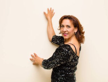 Orta yaşlı güzel bir kadın izole edilmiş ve düz arkaplanda poz veriyor.