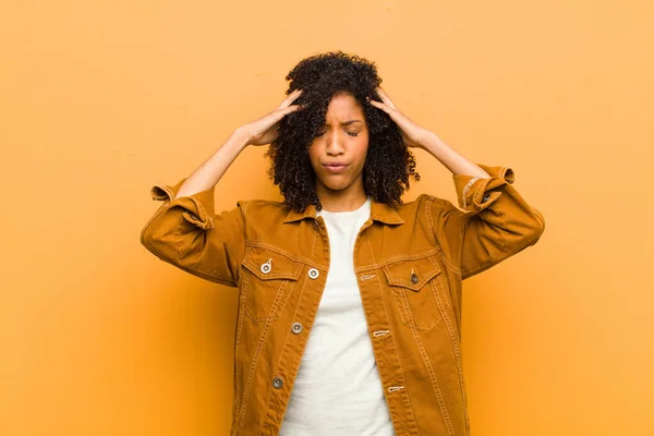 若いかなり黒人女性はオレンジの壁に対して額に手で集中し 思慮深く 触発され ブレインストーミングし 想像しています — ストック写真