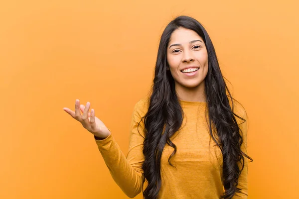 young pretty hispanic woman feeling happy, surprised and cheerful, smiling with positive attitude, realizing a solution or idea against brown wall