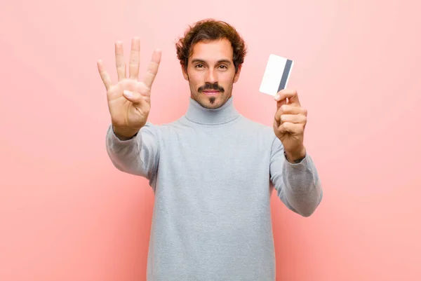 年轻英俊的男人 拿着信用卡靠着粉红的平板墙 — 图库照片