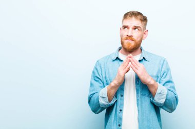 Genç kızıl kafalı entrikacı, komplo kuran, sinsi hileler ve aldatmacalar yapan, yumuşak mavi arka plana karşı kurnaz ve ihanet eden