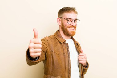 Genç kızıl saçlı, gururlu, tasasız, kendinden emin ve mutlu hisseden, bej arka planda olumlu gülümseyen adam.