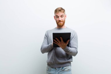 beyaz arka plan karşı bir tablet tutan genç kırmızı kafa adam