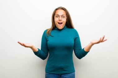Genç bir kadın beyaz arka plana karşı inanılmaz bir sürprizle şaşkın ve şaşkın.