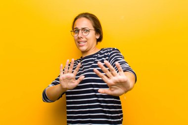 Genç, güzel bir kadın korku ve panik içinde geri çekilip çığlık atıyor. Turuncu arka plandaki bir kabusa tepki veriyor.