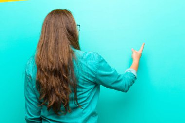 Genç bir kadın dikilip nesneyi işaret ediyor. Kopyalama alanı, dikiz açısı mavi arkaplan