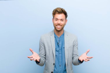 Genç işadamı kendini mutlu, şaşkın, şanslı ve şaşırmış hissediyor. Mavi arka planda inanılmaz