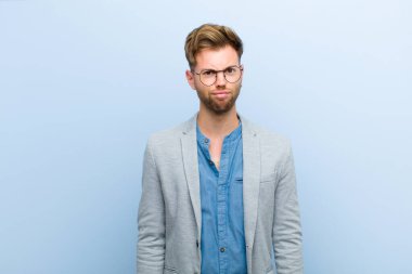 Genç işadamı kendini şaşkın ve kuşkulu hissediyor, merak ediyor ya da mavi arka planda bir karar vermeye çalışıyor.