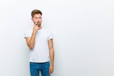 Şaşırmış, gergin, endişeli ya da korkmuş bakışları olan genç adam beyaz arkaplana karşı fotokopi alanına bakıyor.